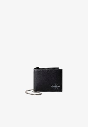 Portefeuille Calvin Klein en cuir noir texturé avec coutures blanches et chaîne argentée attachée sur fond blanc.