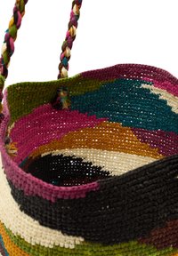 Vävd korg med flerfärgade mönster i rosa, grön, svart och tan. Har ett flätat handtag och en texturerad, öppen vävdesign.