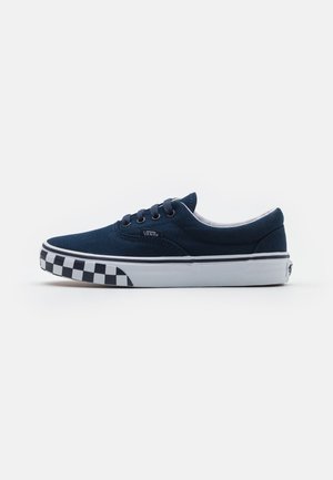 Baskets basses Vans bleu marine avec motif damier noir et blanc sur la semelle et semelle intermédiaire blanche.