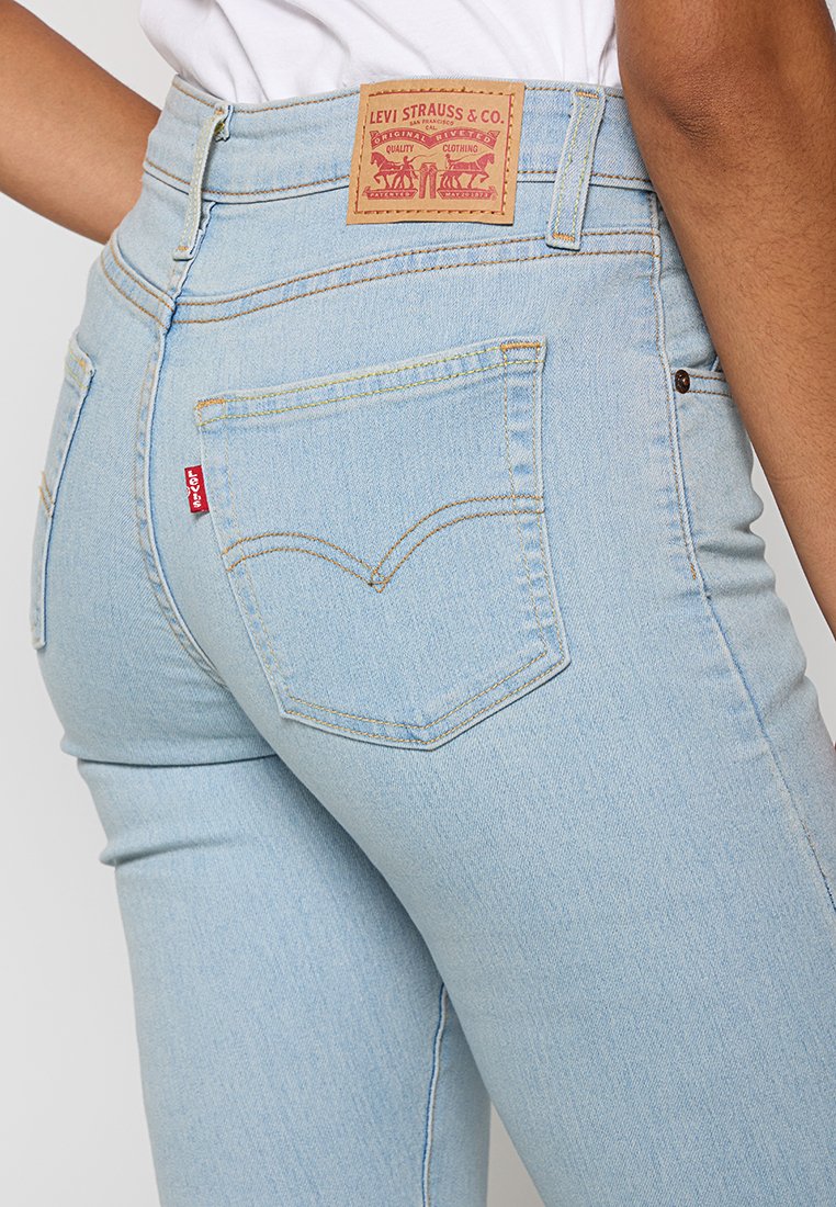 Helle blaue, hochtaillierte Jeans mit einem Leder-Tag von Levi's, ausgestattet mit einem klassischen Rücktaschendesign und kontrastierenden Nähten.