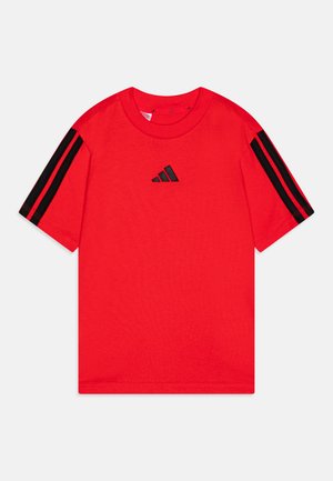 Camiseta roja de manga corta hecha de algodón, con rayas negras en las mangas y una insignia de logo negra en el frente. Escote redondo.