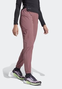 Lätta, rosa joggerbyxor med resårmidja och sidofickor, tillsammans med svarta och gröna sportskor.