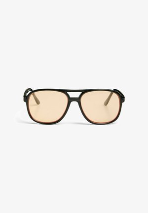 Lunettes style aviateur à monture noire avec verres teintés marron clair, présentées sur fond blanc.