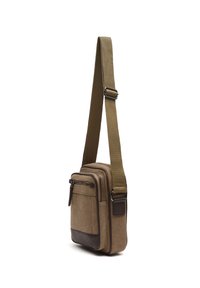 Kleine bruine canvas crossbodytas met verstelbare riem, voorvak met rits en leren accenten aan de onderkant.