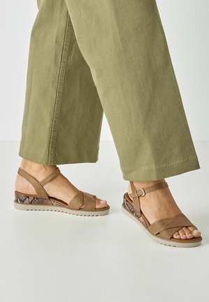 Sandales à lanières en daim marron avec un petit talon compensé, présentant un accent texturé à motif animalier sur le talon et une bride de cheville ajustable.