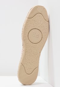 Light-colored shoes with a textured rubber sole, featuring a circular logo with the number "38" and "MADE IN FRANCE" engraved.