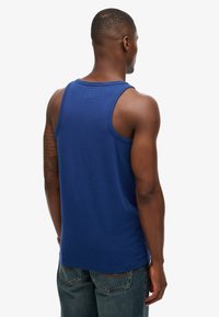 Navyblauwe katoenen tanktop met een ronde hals en brede armsgaten, van achteren getoond, gecombineerd met denim jeans.