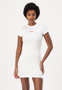 White ribbed bodycon dress with short sleeves, round neck, and a small pink logo at the chest. Smooth texture, fitted silhouette.