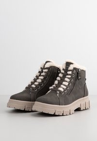 Bottes d'hiver gris foncé à lacets avec semelles épaisses beige clair, doublure en fourrure blanche et détails de fermeture éclair latéraux.