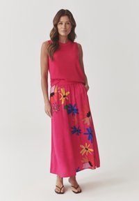 Haut sans manches fuchsia associé à une longue jupe rose avec des motifs floraux multicolores. La tenue présente une coupe décontractée et une texture douce.