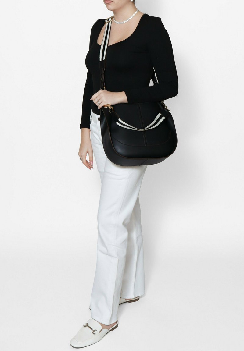 Borsa a spalla in pelle nera con forma curva, caratterizzata da una tracolla a strisce bianche a contrasto, hardware dorato e dettagli delle cuciture.