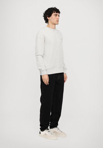 Light gray sweatshirt with ribbed cuffs and hem, paired with black jeans and cream sneakers. The fabric appears soft with a relaxed fit.