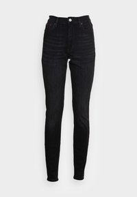 Jeans skinny de cintura alta en denim oscuro, con cierre de botón metálico, diseño de cinco bolsillos y sutiles detalles de costura roja.