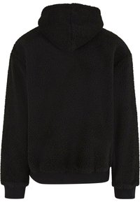 Sweatshirt à capuche noire en molleton texturé. Il présente une coupe décontractée, des poignets et un ourlet côtelés, sans hardware ni motifs visibles.