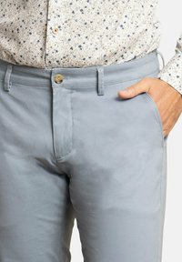 Pantalones de algod�ón azul claro con una textura suave, que cuentan con un cierre frontal de botón, trabillas para cinturón y bolsillos laterales. Acompañados de una camisa con estampado.