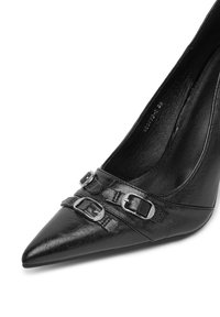 Scarpa nera con punta a stiletto alta, caratterizzata da due fibbie decorative sul cinturino anteriore, realizzata in pelle testurizzata con una fodera interna liscia.