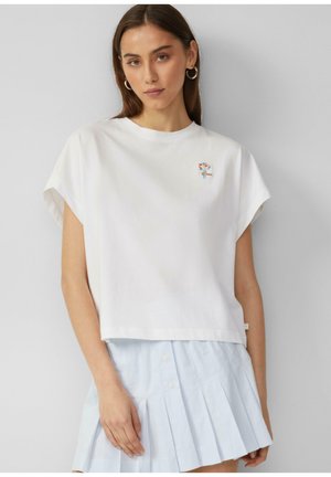 White cotton t-shirt with short sleeve design, featuring a small floral embroidery on the left chest and a straight hemline. Paired with a light blue pleated skirt.