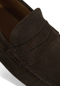 Braune Wildleder-Lederschuhe mit runder Zehenform, versehen mit einer gestickten Akzentuierung und einem dezenten Sattel-Design im Obermaterial. Weicher Textur und legerer Stil.