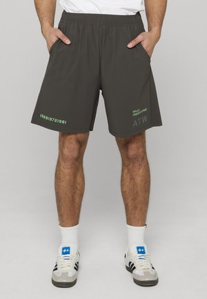 Dunkelgraue Sportshorts mit elastischem Bund, Seitentaschen und grün bedrucktem Text/Design auf der unteren linken Seite. Glatte Textur.