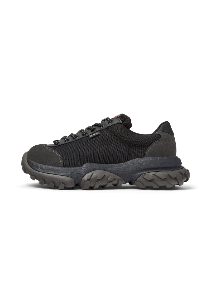 Black athletic sneaker with a textured sole, featuring sturdy laces and a reinforced toe, designed for comfort and durability.