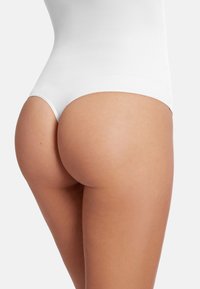 Vit bodysuit med en slät, elastisk textur, som har högskurna ben och minimal ryggtäckning, vilket framhäver formen.