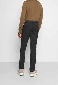 Harmaat kapeat housut, jotka on valmistettu joustavasta kankaasta. Niissä on kaksi takataskua ja keski-korkea vyötärö. Yhdistettynä beigellä värillä varustettuihin lenkkareihin.