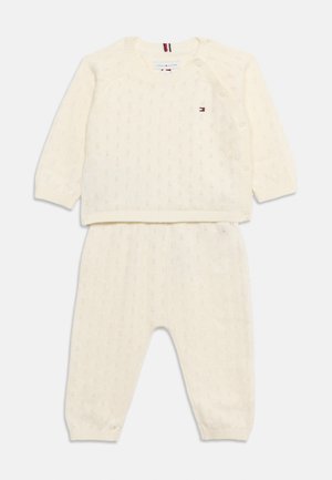 Ensemble pull tricoté couleur crème pour bébé avec pantalon assorti, motif subtil et boutons latéraux sur l’épaule du pull.