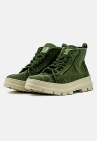 Zapatillas altas de tela verde oscuro con un acabado texturizado y suela de goma de color claro. Presentan un diseño con cordones y una etiqueta de logo en la lengüeta.