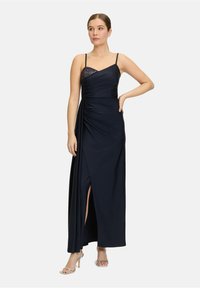 Robe de soirée bleu marine avec bretelles fines, détail froncé et une fente hautement échancrée. Dispose d'une accent en maille sur le corsage pour ajouter de la texture.