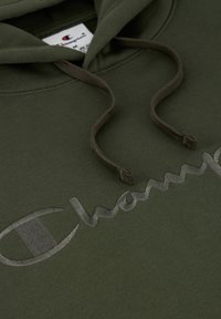 Olijfgroene hoodie met een zachte textuur, voorzien van een groot, reflecterend Champion-logo in lichtgrijs en bijpassende trekkoorden.