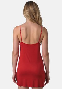Rote Spaghettiträger-Tops mit dünnen verstellbaren Trägern, aus glattem Stoff gefertigt. Verfügt über einen gewellten Saum und eine figurbetonte Silhouette, alles in einer einheitlichen Farbe.