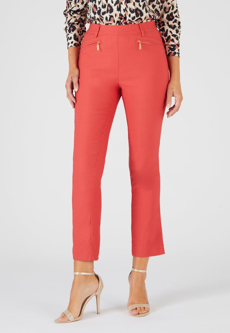 Pantalon rouge à coupe slim, avec deux poches zippées et quincaillerie dorée. Tissu lisse avec une texture légèrement extensible.