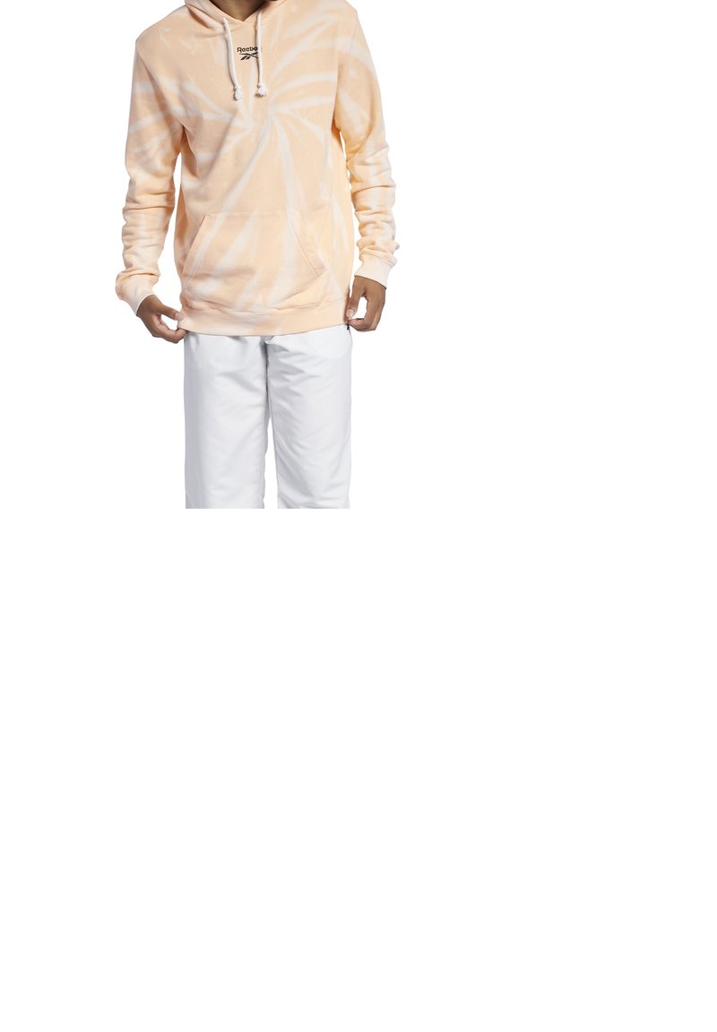 Peach tie-dye hoodie with white spiral pattern, drawstring hood, front pocket, and ribbed cuffs, paired with white pants.