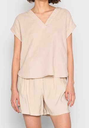 Blusa beige con texture, scollatura a V e maniche corte, abbinata a pantaloni corti beige larghi coordinati. Design semplice e minimalista.