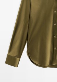 Camicia a maniche lunghe verde oliva, in tessuto liscio, con orlo curvo e polsini con finitura lucida. Bottoni in tono abbinato.