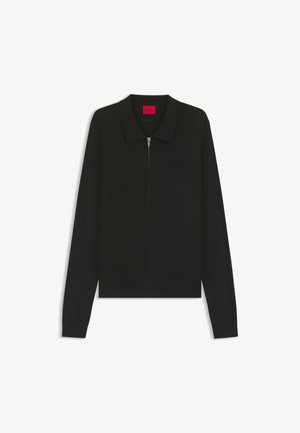 Cardigan nero con zip, colletto, maniche lunghe e taschino sul petto. Il tessuto appare liscio con una leggera elasticità. Etichetta del marchio in rosa brillante.