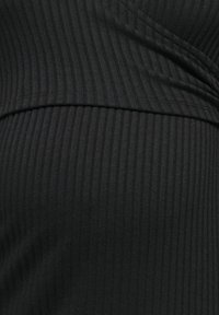 Czarny prążkowany materiał z pionowymi paskami o miękkiej fakturze tworzy dopasowany fason z detalem krzyżowym przy dekolcie.