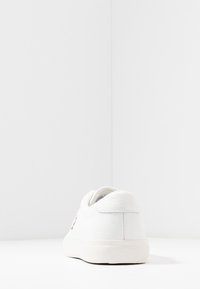 Białe skórzane tenisówki o gładkiej fakturze, zaokrąglonym kształcie i minimalistycznym designie. Posiadają subtelne logo na pięcie i gumową podeszwę.