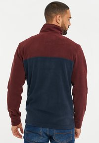 Pullover in pile con collo alto, con sezioni superiori color marmorizzato e sezioni inferiori blu navy. Morbido al tatto, maniche lunghe e vestibilità casual.