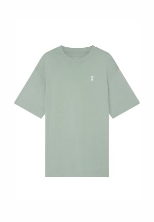 Salbeigrünes T-Shirt mit kurzen Ärmeln und rundem Ausschnitt, mit kleinem weißem Logo auf der linken Brust, flach liegend vor weißem Hintergrund gezeigt.