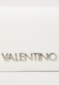 Bílá kožená peněženka s embosovaným logem "VALENTINO" ve lesklém stříbře. Hladký povrch s tónováním stehu podél okrajů.