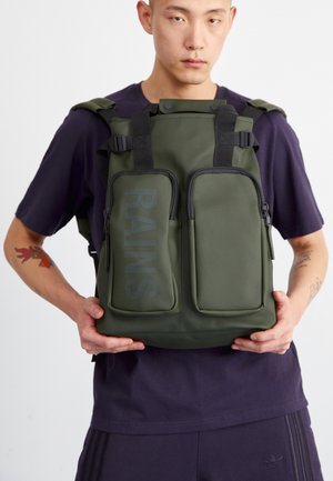 Green waterproof backpack with roll-top closure, two front zip pockets, adjustable straps, and large "RAINS" logo on front.