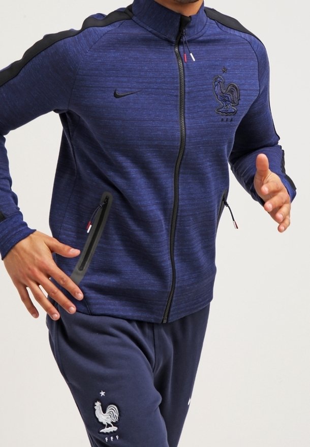 Giacca sportiva zip-up blu navy con colletto alto, dettagli neri ed logo della Francia ricamato. Vestibilità slim con tasche laterali e tessuto texturizzato.