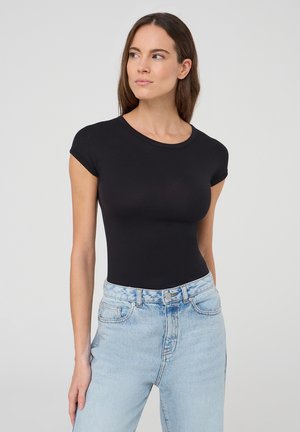 Body corto nero a maniche corte con design aderente e scollatura rotonda, abbinato a jeans in denim azzurro chiaro a vita alta. Texture liscia.