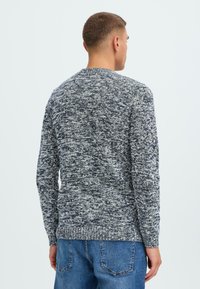 Pulover tricotat texturat în gri și bleumarin, cu mâneci lungi și decolteu rotund. Materialul are un model mixt și tiv cu nervuri.