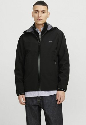Chaqueta impermeable negra con cremallera frontal, forro interior gris y bolsillos laterales. Cuenta con capucha y puños elásticos.