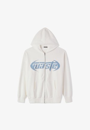 Felpa bianca con zip, cappuccio, tasche frontali e testo sbiadito blu "waste" sul petto in un font stilizzato.