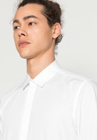 Witte blouse met kraag, voorzien van een knoopsluiting aan de voorkant, een gladde textuur en een op maat gemaakte pasvorm met een schone, minimalistische uitstraling.