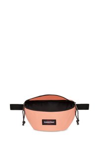 Persikofärgad tygpåse med svart inredning, rundad form, dragkedjestängning och en sidrest. Har en svart Eastpak-logotypapplikation.