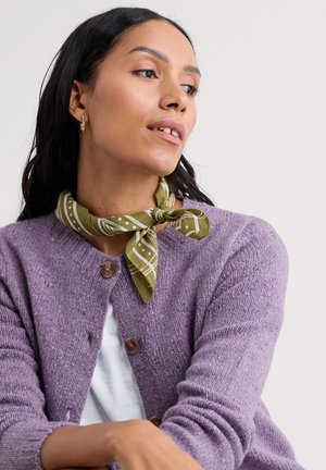 Lavendelfarvet strikket cardigan med brune knapper, parret med et grønt tørklæde med hvide mønstre bundet om halsen. Hvid top under.